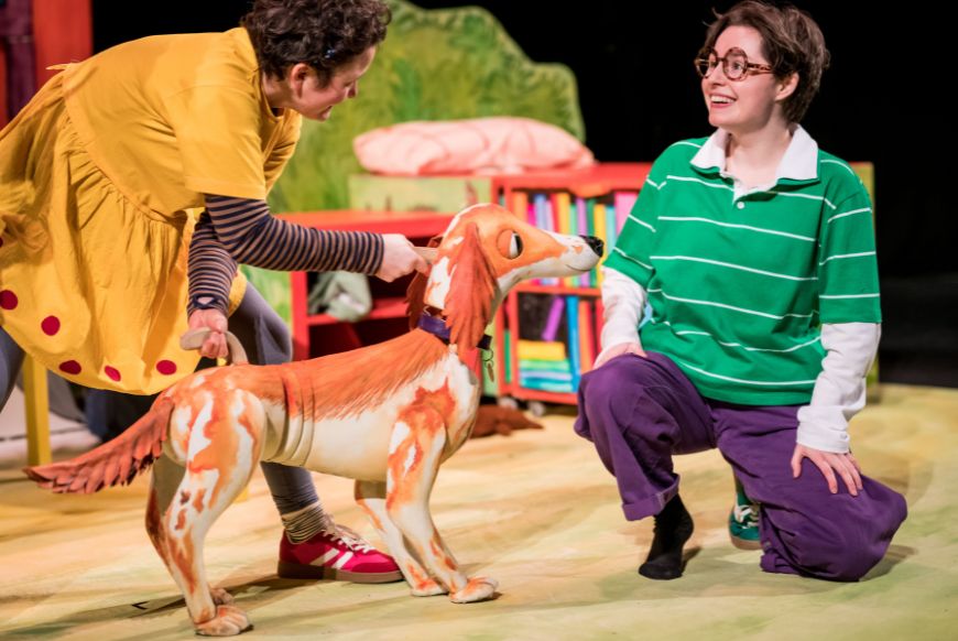 a dog puppet on stage with a boy in a green shirt